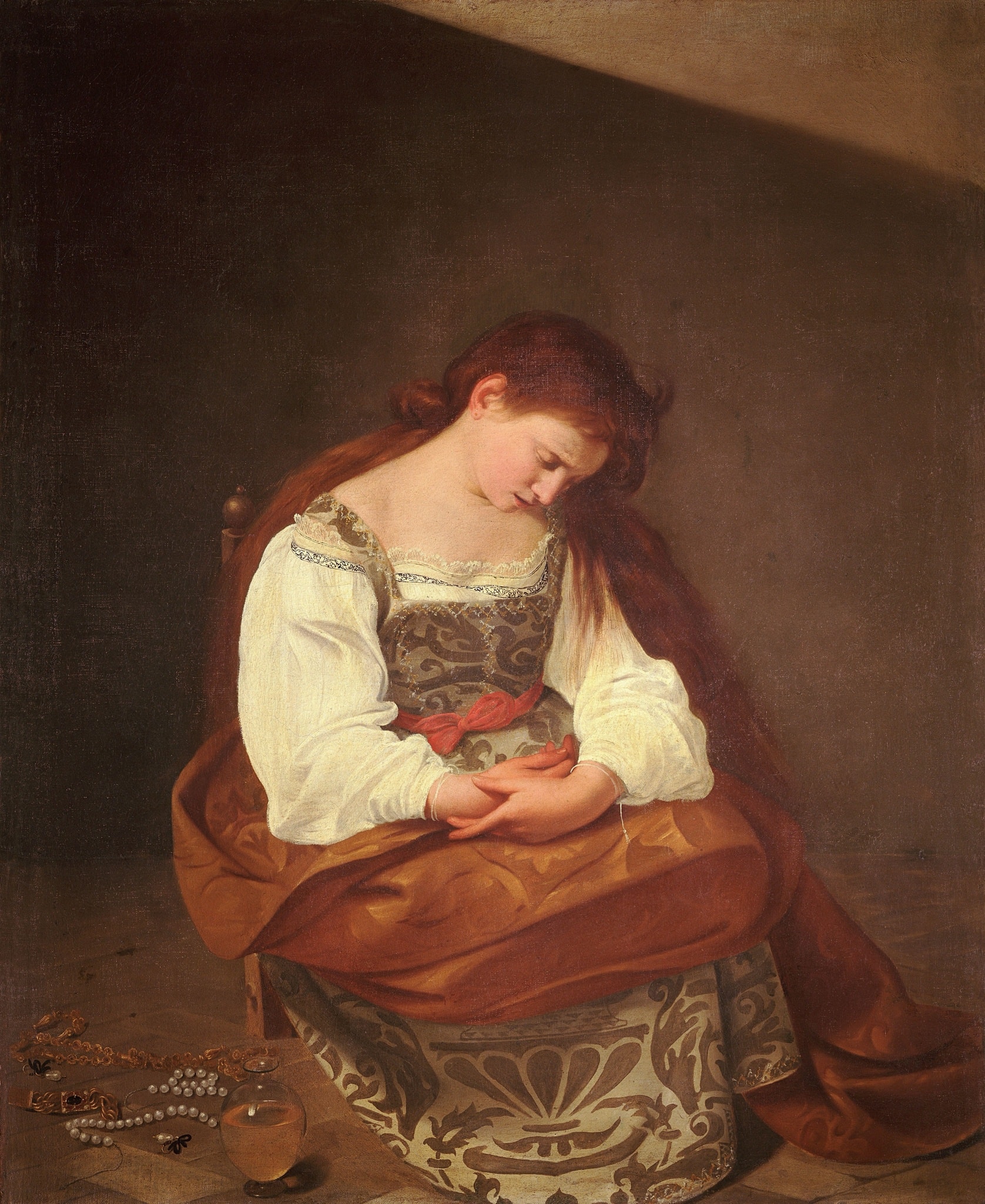 She sits on a low chair, her head bowed toward her loosely folded hands. The patterned dress and pale blouse retain their ordinary texture in the sparse room.