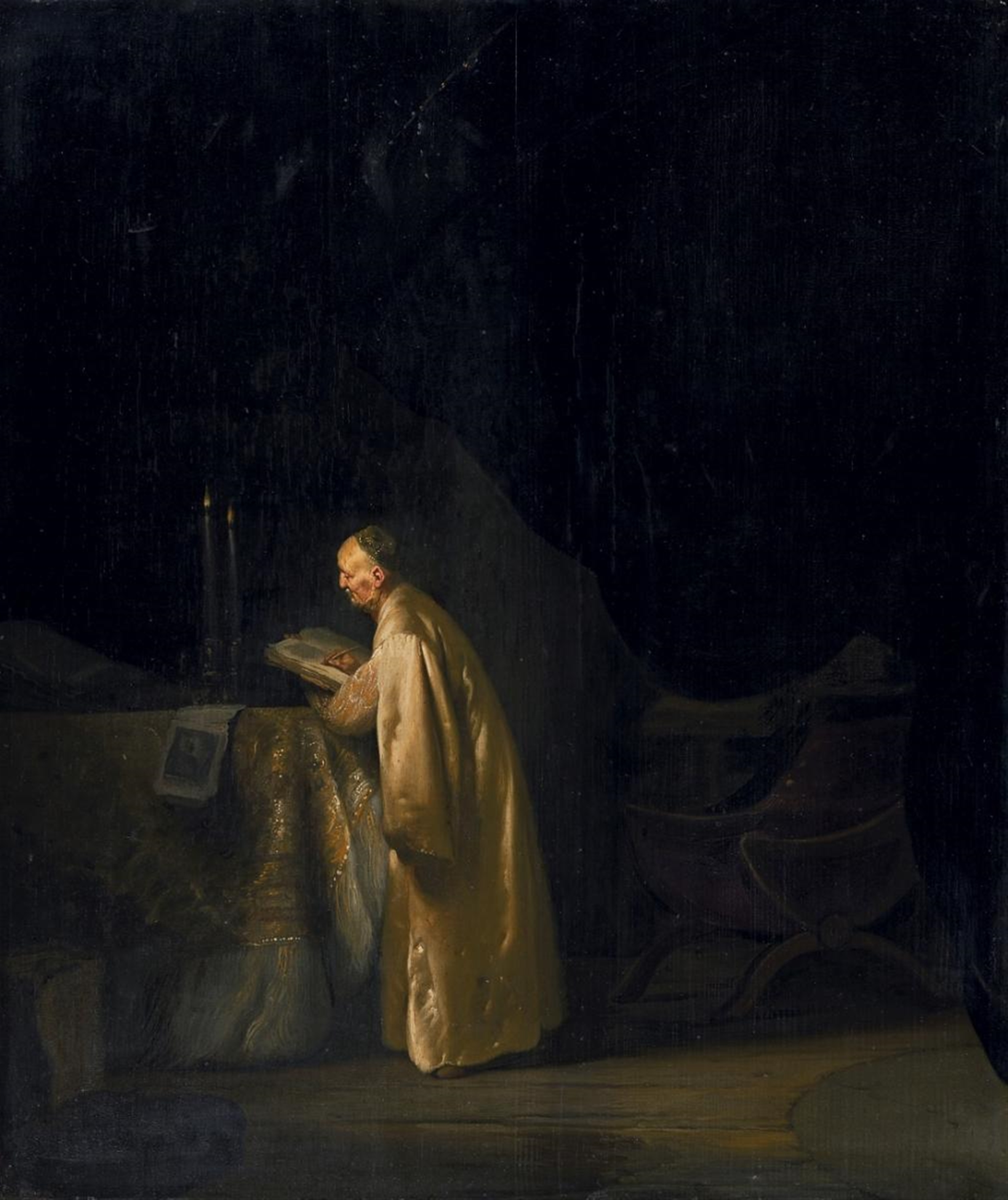 An elderly, bearded Zechariah in a golden robe bends over a writing surface in a dim room, illuminated against a dark architectural background.