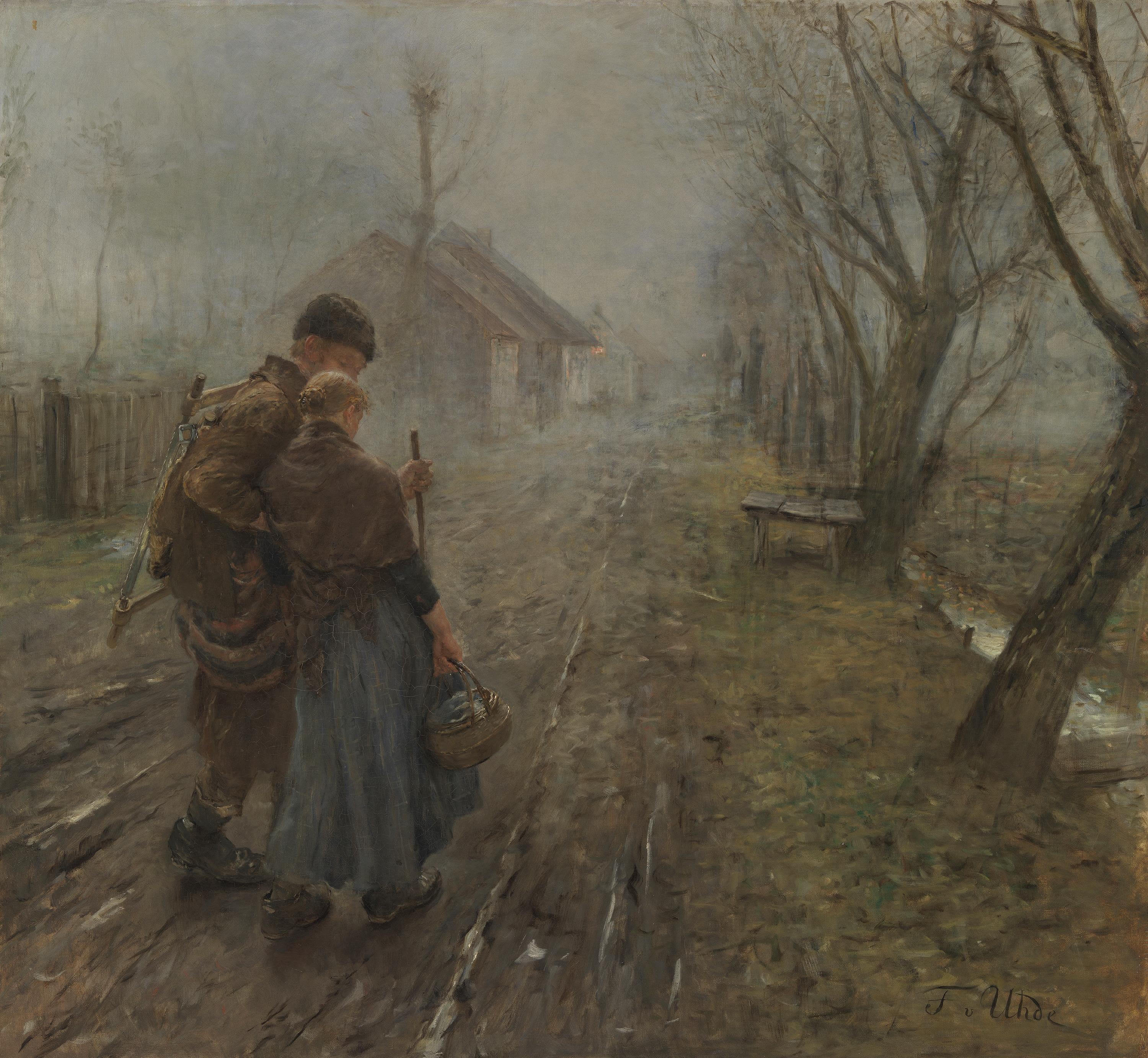 A man supports a pregnant woman as they walk along a muddy village road beside bare trees and a stream.