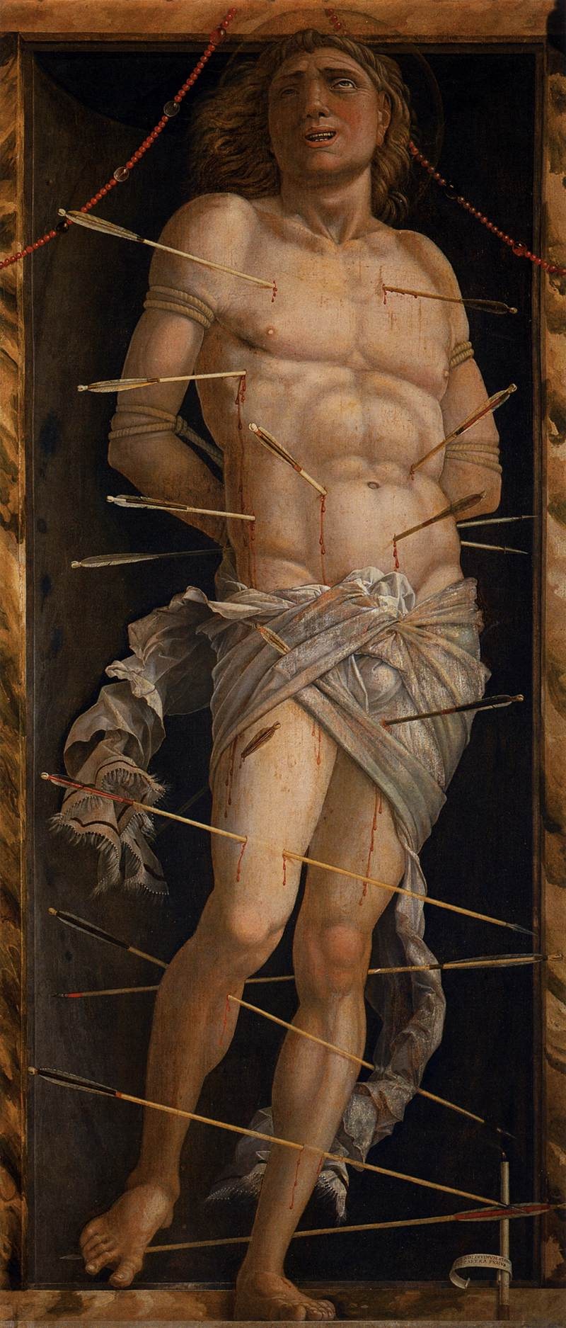 Sebastian stands against a dark background with numerous arrows crossing his torso and legs and pale fabric wound around his hips.