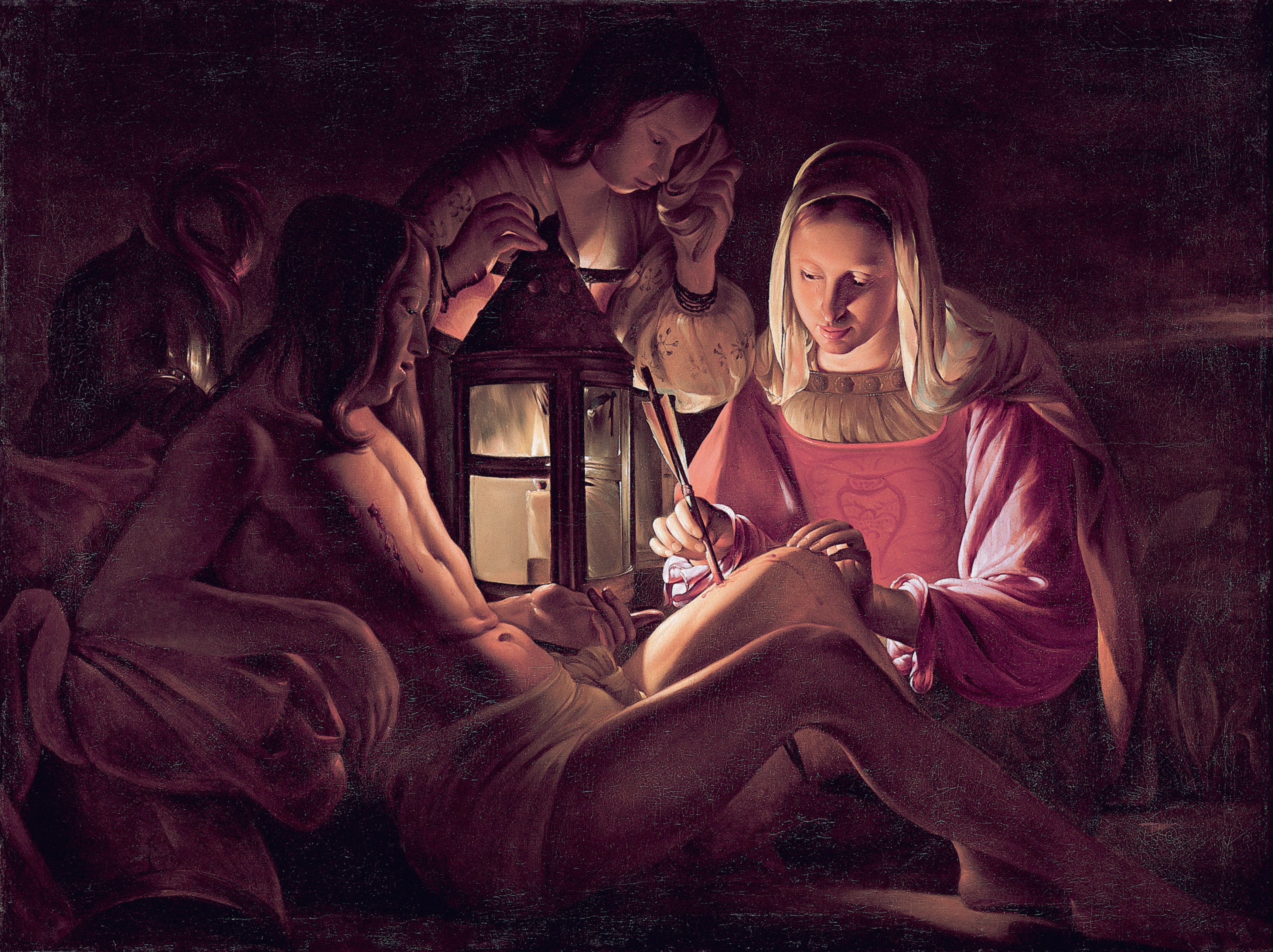 Women tend Sebastian’s outstretched body in a dark room, their faces and hands lit by a lantern beside him.